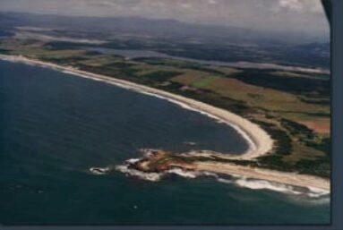 Aerial view of curving coastline and rocky headland